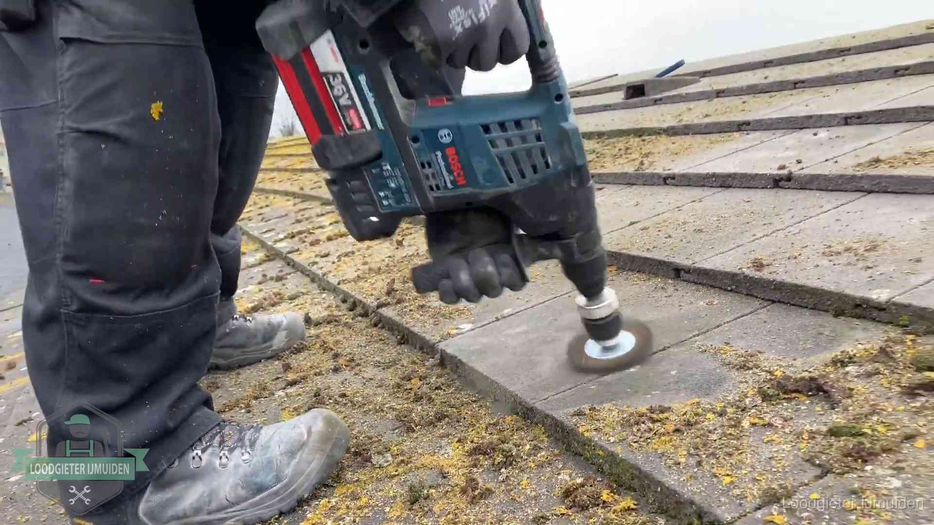 Betonnen dakpannen worden machinaal gereinigd tijdens dakonderhoud in IJmuiden