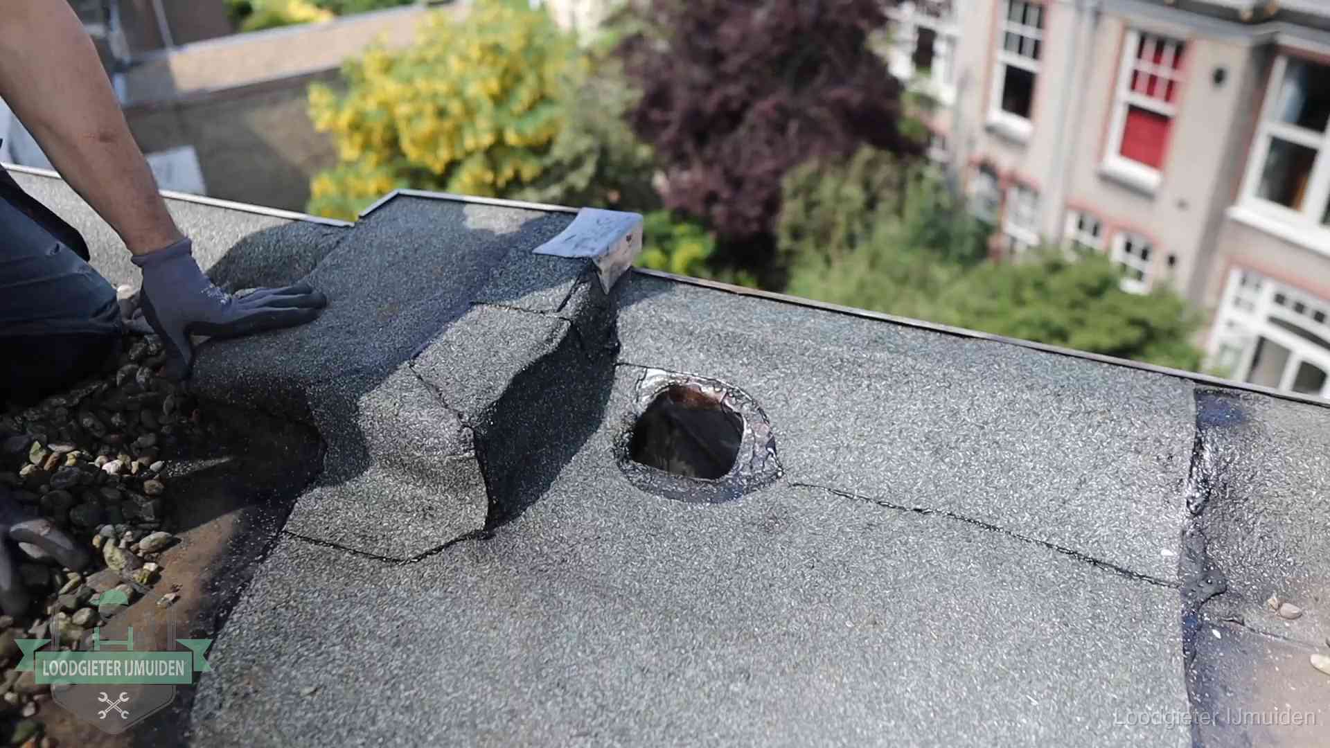 Loodgieter inspecteert een beschadigd bitumen plat dak tijdens een daklekkage-inspectie in IJmuiden