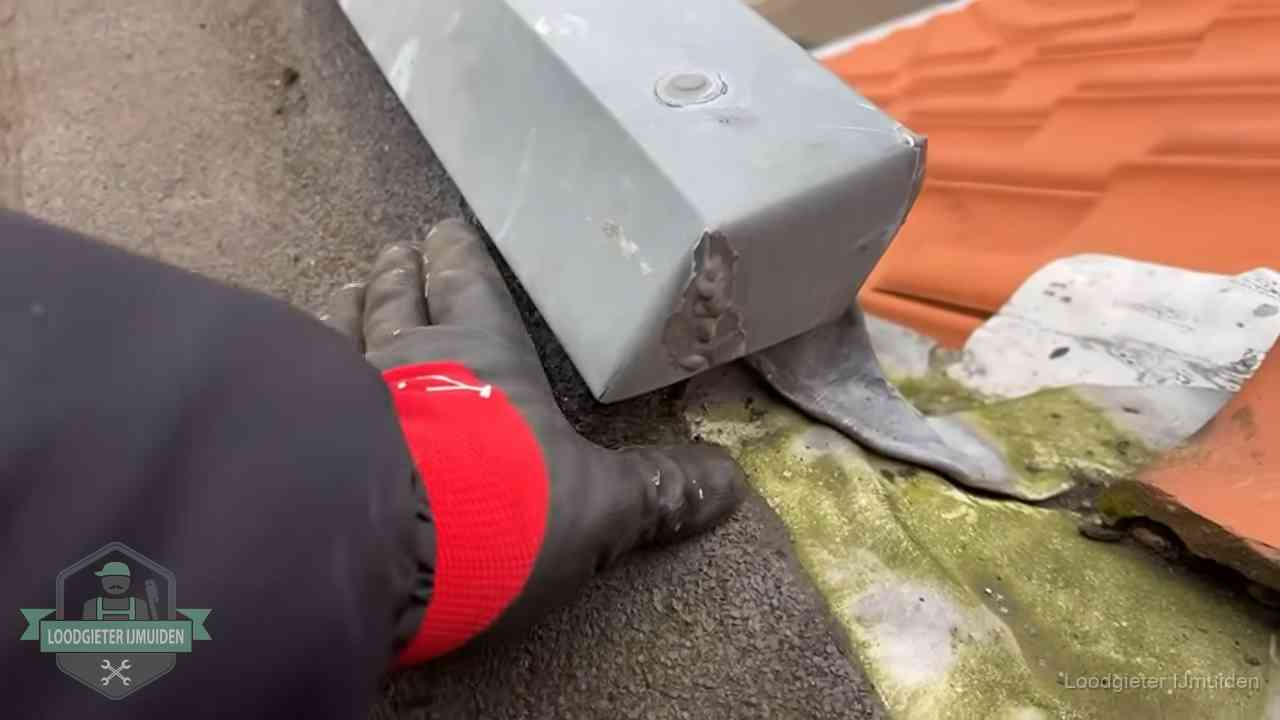 Controle van een zinken hemelwaterafvoer met loodslab bij dakpannen in IJmuiden