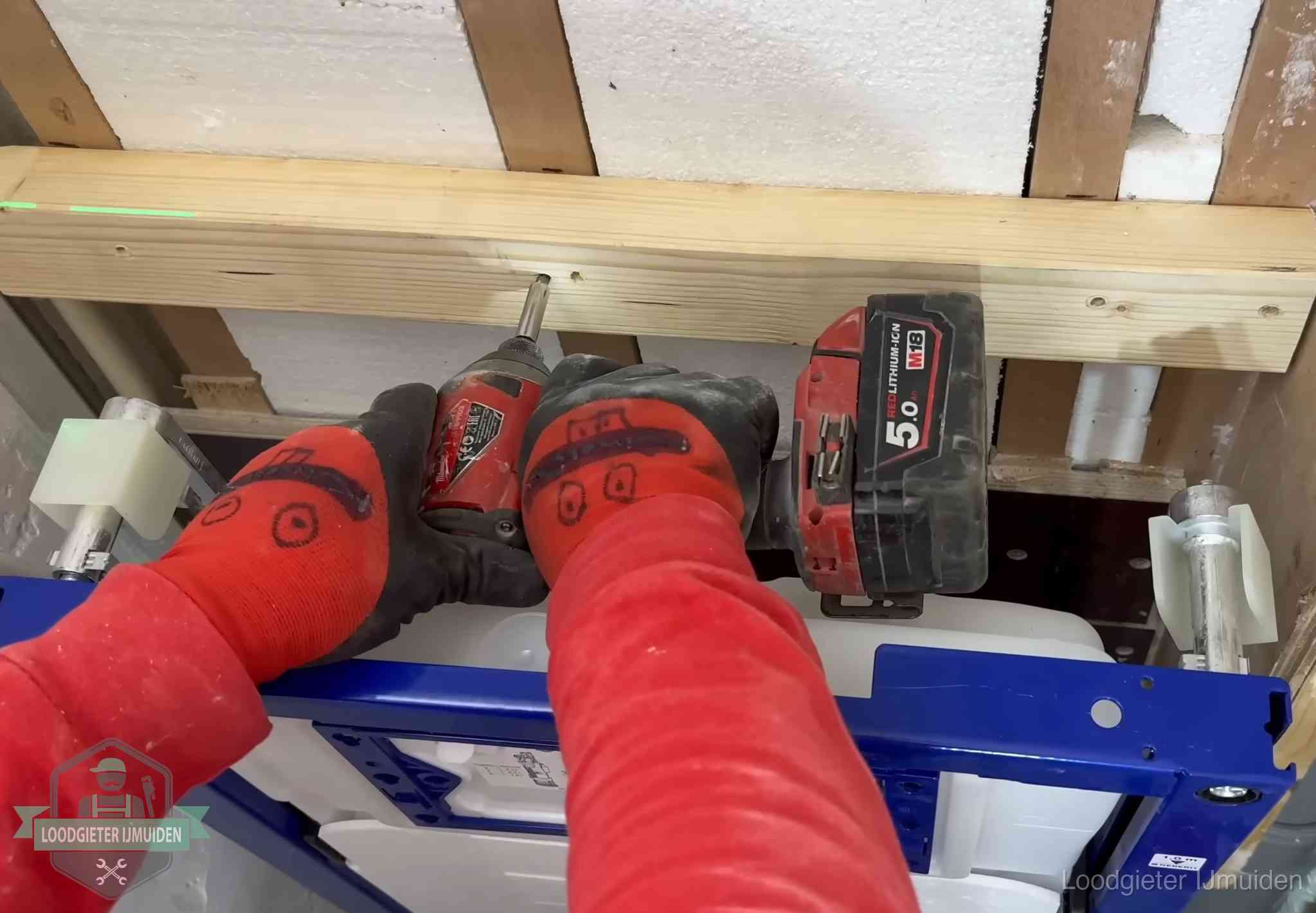 Monteur bevestigt een inbouwreservoir voor een hangend toilet in IJmuiden