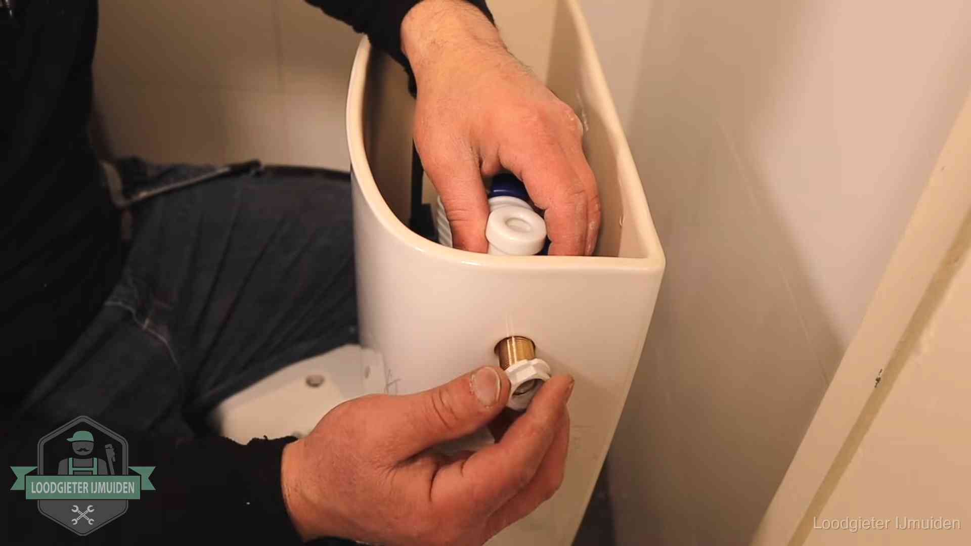 Loodgieter monteert de vlotterkraan van een stortbak bij een toilet in IJmuiden