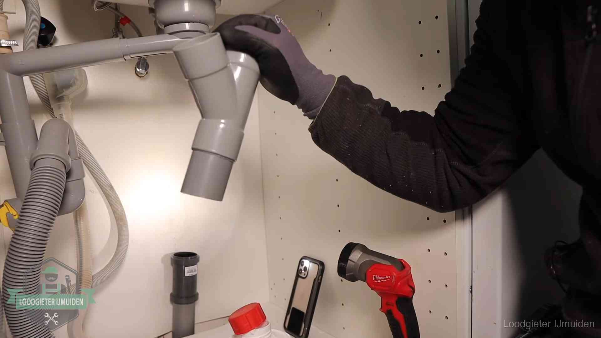 Rioollucht in huis verhelpen in IJmuiden Loodgieter demonteert het sifon- en afvoerwerk onder een gootsteen in IJmuiden bij stankklachten