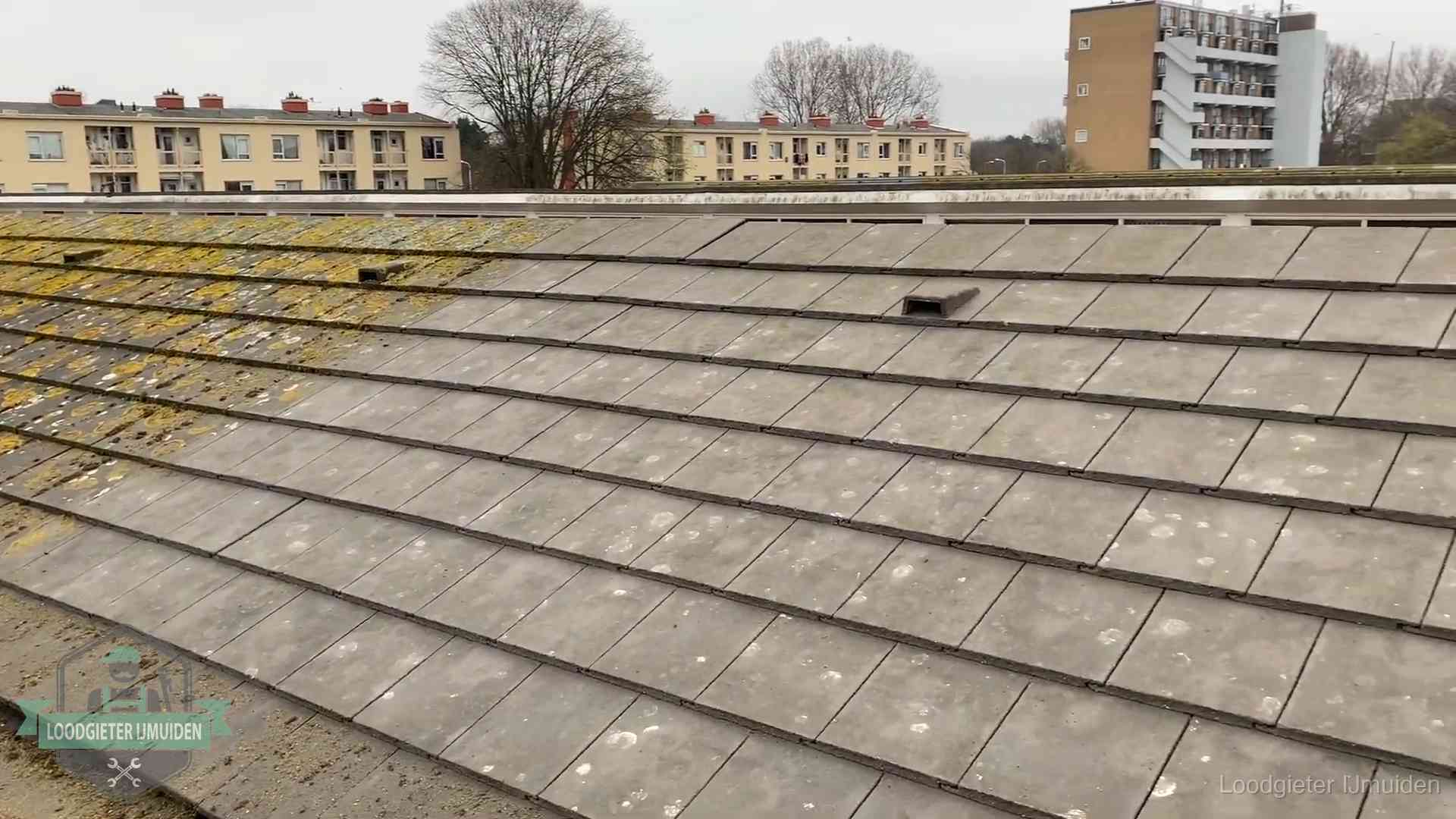 Schuin dak met betonpannen vol mos in IJmuiden, een risico op lekkage bij de pannen