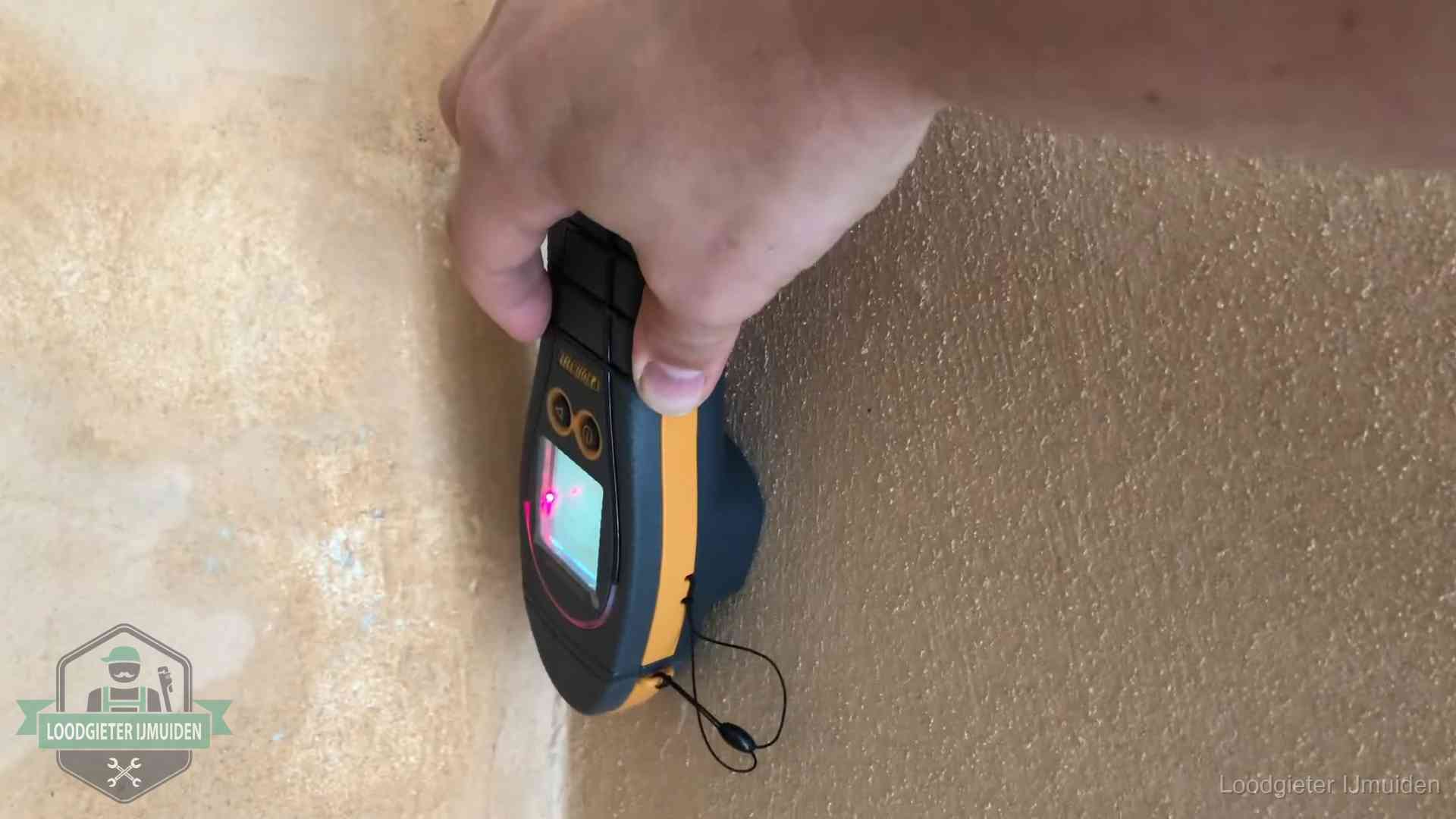 Vochtmeter tegen een muur met vochtplekken tijdens het opsporen van een daklekkage in IJmuiden