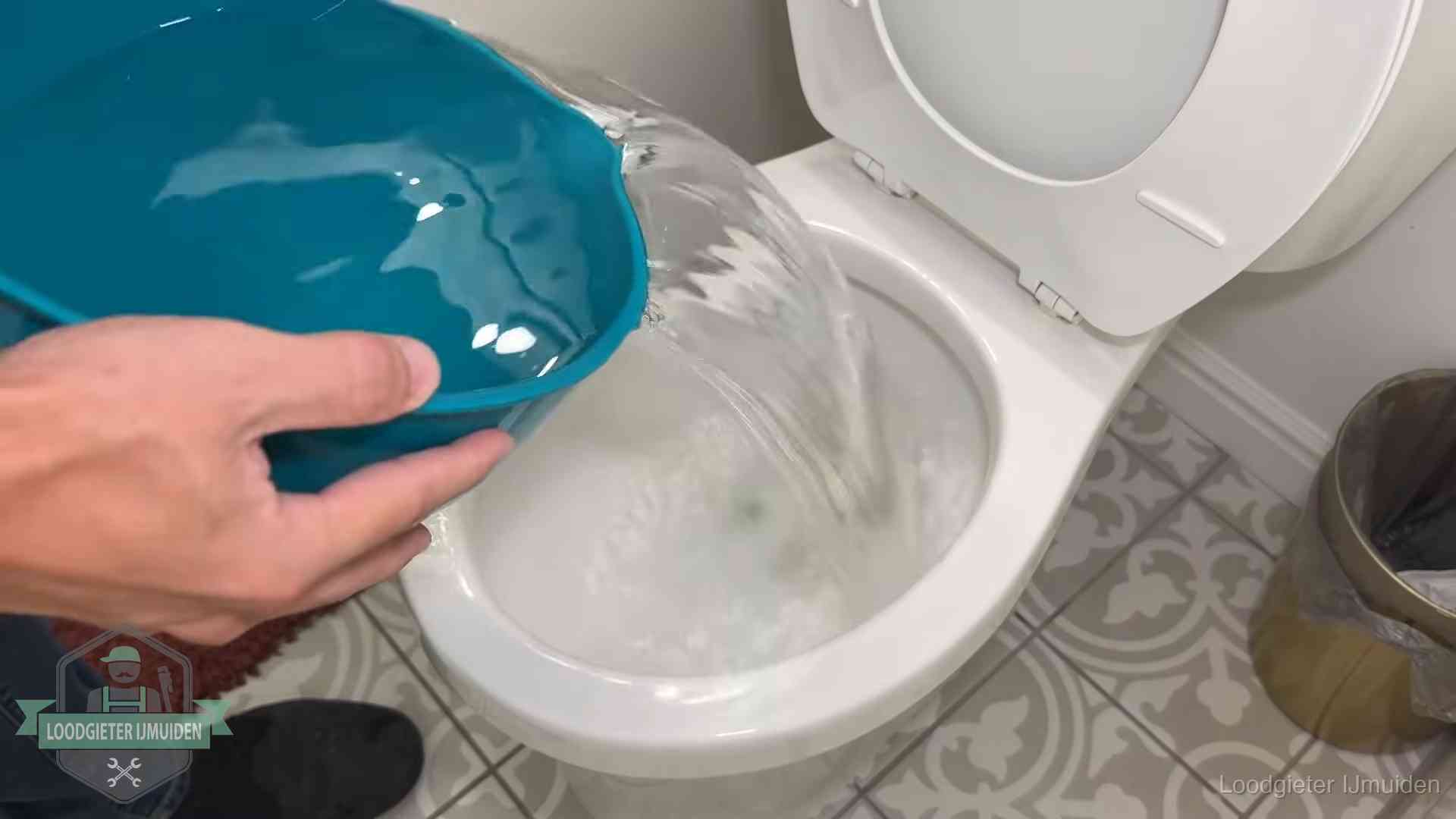 Warm water wordt voorzichtig in de wc-pot gegoten in IJmuiden