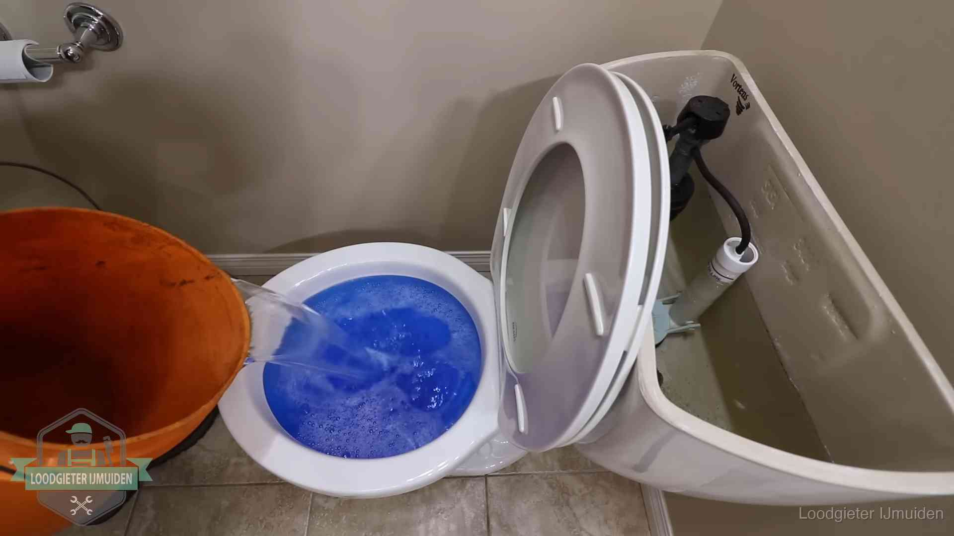 Water bij de wc-pot wordt met een emmer weggewerkt om schade te beperken in IJmuiden